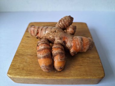 Tahta servis tahtasındaki zerdeçal ritmi. Zerdeçal öncelikle Asya mutfağında ve potansiyel sağlık yararları için yemek pişirmede bir baharat olarak kullanılır. Curcuma longa bitkisinin zencefille ilgili bir ritmi.