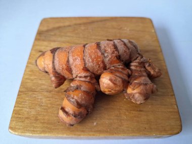 Tahta servis tahtasındaki zerdeçal ritmi. Zerdeçal öncelikle Asya mutfağında ve potansiyel sağlık yararları için yemek pişirmede bir baharat olarak kullanılır. Curcuma longa bitkisinin zencefille ilgili bir ritmi.