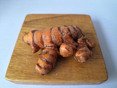 Tahta servis tahtasındaki zerdeçal ritmi. Zerdeçal öncelikle Asya mutfağında ve potansiyel sağlık yararları için yemek pişirmede bir baharat olarak kullanılır. Curcuma longa bitkisinin zencefille ilgili bir ritmi.