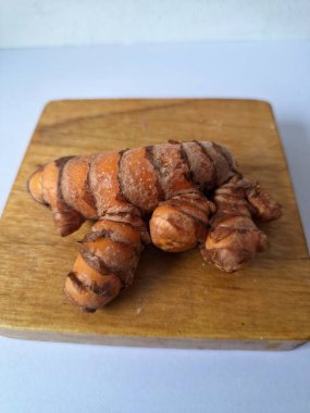 Tahta servis tahtasındaki zerdeçal ritmi. Zerdeçal öncelikle Asya mutfağında ve potansiyel sağlık yararları için yemek pişirmede bir baharat olarak kullanılır. Curcuma longa bitkisinin zencefille ilgili bir ritmi.