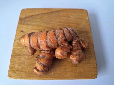 Tahta servis tahtasındaki zerdeçal ritmi. Zerdeçal öncelikle Asya mutfağında ve potansiyel sağlık yararları için yemek pişirmede bir baharat olarak kullanılır. Curcuma longa bitkisinin zencefille ilgili bir ritmi.