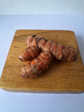 Tahta servis tahtasındaki zerdeçal ritmi. Zerdeçal öncelikle Asya mutfağında ve potansiyel sağlık yararları için yemek pişirmede bir baharat olarak kullanılır. Curcuma longa bitkisinin zencefille ilgili bir ritmi.