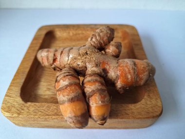 Tahta servis tahtasındaki zerdeçal ritmi. Zerdeçal öncelikle Asya mutfağında ve potansiyel sağlık yararları için yemek pişirmede bir baharat olarak kullanılır. Curcuma longa bitkisinin zencefille ilgili bir ritmi.