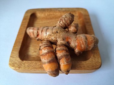 Tahta servis tahtasındaki zerdeçal ritmi. Zerdeçal öncelikle Asya mutfağında ve potansiyel sağlık yararları için yemek pişirmede bir baharat olarak kullanılır. Curcuma longa bitkisinin zencefille ilgili bir ritmi.