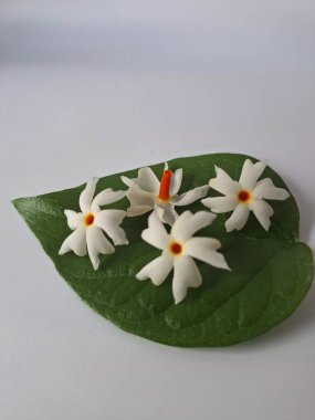 Parijat çiçeği (Nyctanthes ağaç-tristis) beyaz arkaplanda izole edilmiş parijat yaprağının üzerinde