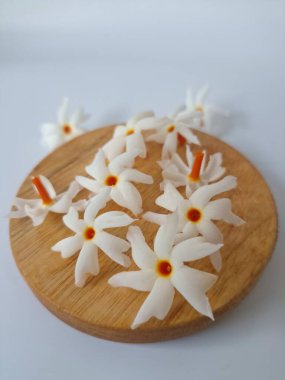 Servis tahtasındaki taze parijat çiçekleri. Çeşitli kullanımları var, hem tıbbi hem de kültürel. Ayurvedic tıpta ateş, öksürük ve soğuk algınlığını tedavi etmek için kullanılır. Çiçekler Hindu ayinlerinde ve tanrılara adak olarak da kullanılır.