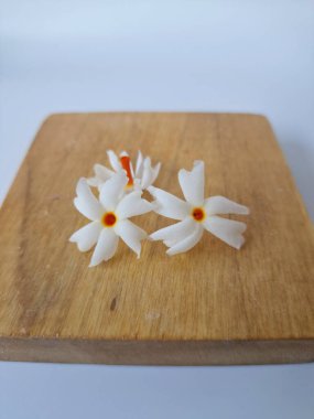 Servis tahtasındaki taze parijat çiçekleri. Çeşitli kullanımları var, hem tıbbi hem de kültürel. Ayurvedic tıpta ateş, öksürük ve soğuk algınlığını tedavi etmek için kullanılır. Çiçekler Hindu ayinlerinde ve tanrılara adak olarak da kullanılır.