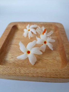 Servis tahtasındaki taze parijat çiçekleri. Çeşitli kullanımları var, hem tıbbi hem de kültürel. Ayurvedic tıpta ateş, öksürük ve soğuk algınlığını tedavi etmek için kullanılır. Çiçekler Hindu ayinlerinde ve tanrılara adak olarak da kullanılır.