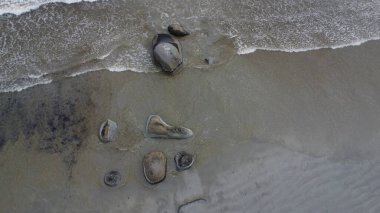Kumlu deniz tabanına saçılmış pürüzsüz granit taşlardan oluşan hava manzarası gelgit dalgalarıyla yavaşça kıvrılarak kaya ve deniz arasındaki ebedi dansı gözler önüne seriyor..