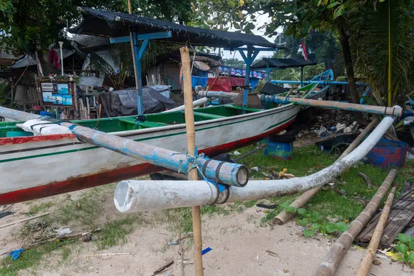 Bali, Endonezya - 22 Aralık 2024: Mavi direkli bir tekne. Direk bir boruya bağlı. Tekne kumda oturuyor.