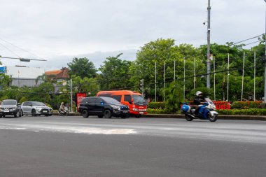 Bali, Endonezya - 22 Aralık 2024: Bali 'de kavşak. Beyaz araba arka planda reklam panosuyla caddeden aşağı doğru gidiyor..