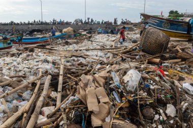 Bali, Endonezya - 22 Aralık 2024: Plaj çöp ve molozlarla kaplıdır. Olay yeri kaotik ve dağınık, insanlar etrafa dağılmış durumda. Sahne hüzün ve umutsuzluktur.
