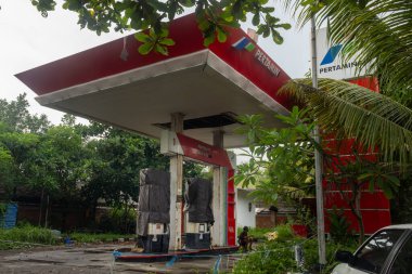 Bali, Endonezya - 22 Aralık 2024: Bali 'de terk edilmiş Pertamina benzin istasyonu. İstasyon boş ve etrafında bir sürü ağaç var.