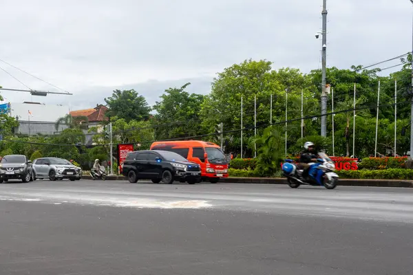Bali, Endonezya - 22 Aralık 2024: Bali 'de kavşak. Beyaz araba arka planda reklam panosuyla caddeden aşağı doğru gidiyor..