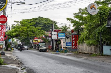Bali, Endonezya - 10 Aralık 2024: bir sürü ağaç ve bir ramen restoranı tabelası olan cadde. Sokaklar arabalar ve motosikletlerle dolu.