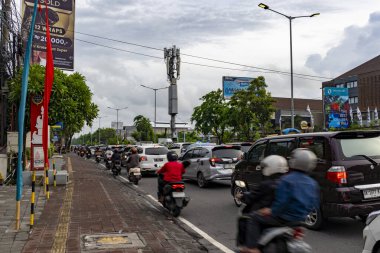 Bali, Endonezya - 10 Aralık 2024: Birçok araba ve motosikletle dolu bir cadde. Manzara kaotik ve hareketli. Bu görüntünün ana fikri yoğun trafiği olan bir şehir caddesi.