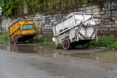 Bali, Endonezya - 28 Aralık 2024: Yolun kenarında iki çöp arabası duruyor. Biri sarı, diğeri beyaz.