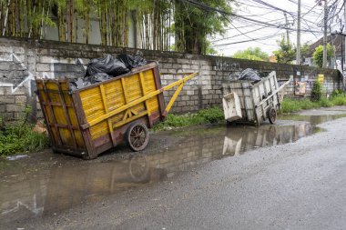 Bali, Endonezya - 28 Aralık 2024: Yolun kenarında iki çöp arabası duruyor. Biri sarı, diğeri beyaz.