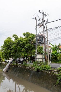 Bali, Endonezya - 28 Aralık 2024: Nehir iki ev arasında akıyor. Su bulanık ve evler de eski. Sahne kasvetli ve davetsiz.