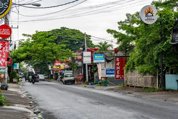 Bali, Endonezya - 10 Aralık 2024: bir sürü ağaç ve bir ramen restoranı tabelası olan cadde. Sokaklar arabalar ve motosikletlerle dolu.