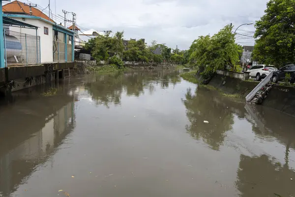 Bali, Endonezya - 28 Aralık 2024: Nehir iki ev arasında akıyor. Su bulanık ve evler de eski. Sahne kasvetli ve davetsiz.