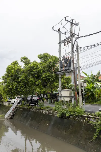 Bali, Endonezya - 28 Aralık 2024: Nehir iki ev arasında akıyor. Su bulanık ve evler de eski. Sahne kasvetli ve davetsiz.