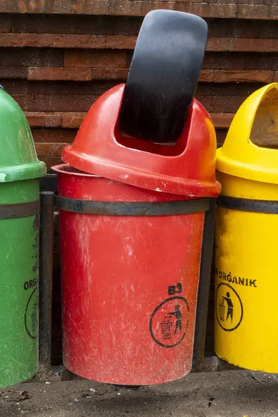 Arka arkaya üç çöp kutusu dizilmiş, her birinin rengi farklı. Yeşil organik için, sarı inorganik için, kırmızı ise zehirli atık için..