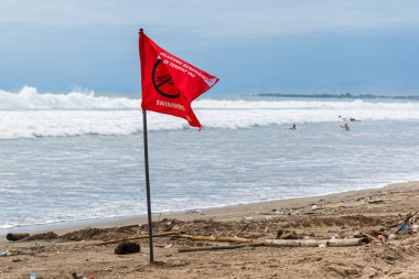 Bali, Endonezya - 11 Aralık 2024: Üzerinde yüzmenin yasak olduğu kırmızı bayrak bir plajda. Rüzgarda dalgalanan bayrak