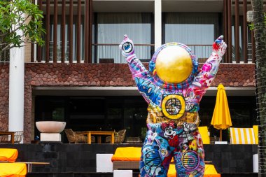 Bali, Endonezya - 11 Aralık 2024: Büyük, renkli ve çok detaylı astronot heykeli bir binanın önünde duruyor. Heykel grafiti ile kaplanmış ve altın bir miğferi var..