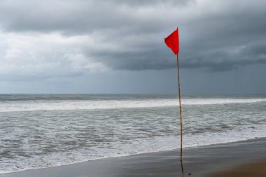 Bali, Endonezya - 11 Aralık 2024: bir sahilde kırmızı bayrak. Rüzgarda dalgalanan bayrak