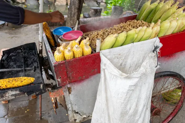 Adam el arabasında mısır pişiriyor. Araba mısır ve fıstık dolu.