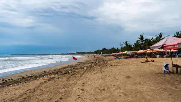 Bali, Endonezya - 11 Aralık 2024: Kuta Sahili Bali, gündüz güneşlenen insanlar ve sahil boyunca birçok şemsiyeyle