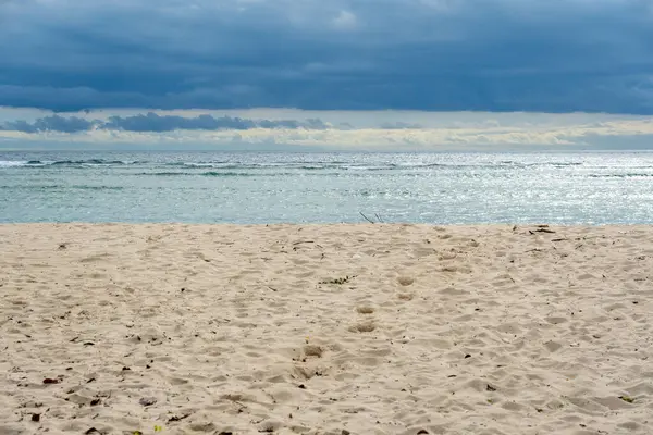 Arka planda bulutlu bir gökyüzü olan plaj. Gökyüzü bulutlu ve su sakin.