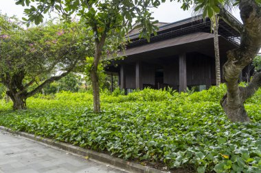 Önünde büyük yeşil bir ağaç olan ev. Ev yemyeşil bir bahçeyle çevrili.