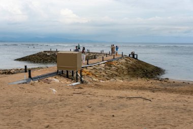 Bali, Endonezya - 17 Aralık 2024: İnsanlar sahilde yürüyor. Gökyüzü bulutlu.