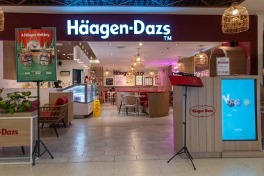 Bali, Endonezya - 17 Aralık 2024: Bali 'deki Icon Bali Alışveriş Merkezi. Haagen-Dazs mağazasının parlak pembe ve beyaz bir renk şeması var, dışarıya birkaç saksı ve sandalye yerleştirilmiş..