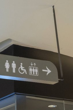 Bali, Endonezya - 17 Aralık 2024: Bali 'deki Icon Bali Alışveriş Merkezi. Tavandan sarkan tuvalet tabelasında bir adam, bir kadın ve bir çocuk vardı. İşaret sağı gösteriyor.