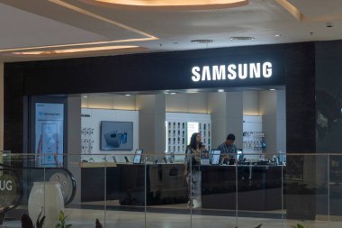 Bali, Endonezya - 17 Aralık 2024: Bali 'deki Icon Bali Alışveriş Merkezi. Tezgahın arkasında bir adam dururken Samsung mağazası. Dükkan açık ve duvarında bir saat var.