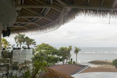 Bali, Endonezya - 17 Aralık 2024: Bali 'deki Icon Bali Alışveriş Merkezi. Arka planda palmiye ağaçları olan bir balkondan okyanus manzarası. Manzara huzurlu ve rahatlatıcı.