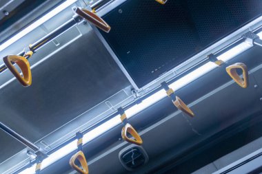 Parlak bir ışık saçan otobüs rayların üzerinde. Tırabzanlar turuncu ve sarı ve tavandan sarkıyor. Işık tırabzanların üzerinde parlıyor.