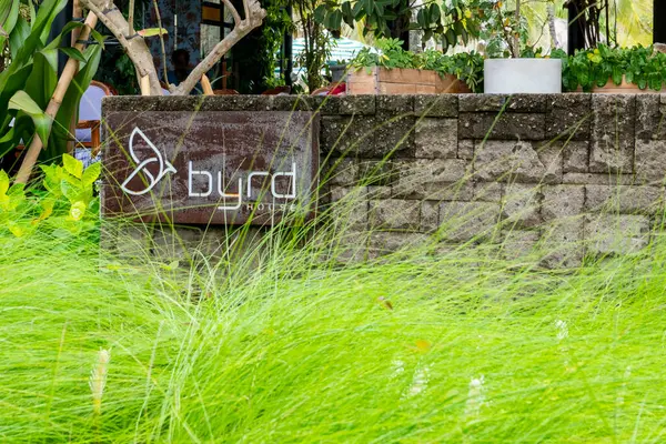 Bali, Endonezya - 17 Aralık 2024 Byrd 'ün imzası bir çimen duvarının yanında. Tabela kahverengi ve beyaz ve üzerinde bir kelebek var. Çimler uzun ve yeşil