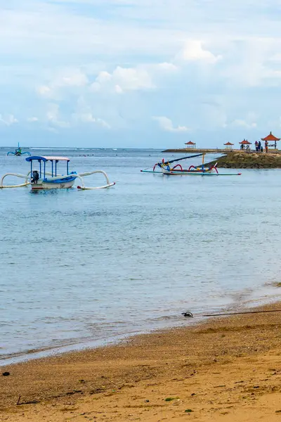 Bali, Endonezya - 17 Aralık 2024: Küçük mavi tekne suda duruyor. Gökyüzü bulutlu ve su sakin.