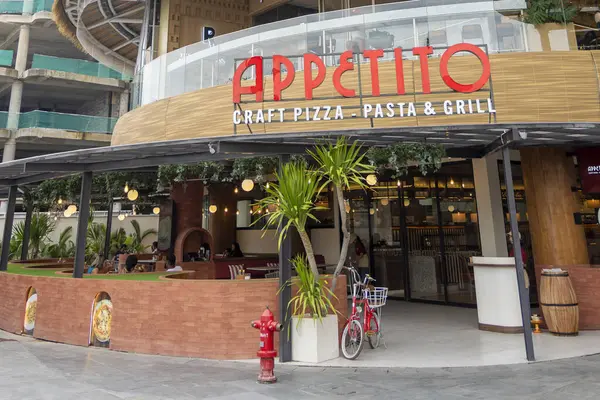 Bali, Endonezya - 17 Aralık 2024: Bali 'deki Icon Bali Alışveriş Merkezi. Appetito adlı restoranda kırmızı-beyaz bir tabela var. Restoranın bir verandası ve bisiklet parkı var.