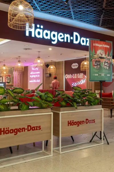 Bali, Endonezya - 17 Aralık 2024: Bali 'deki Icon Bali Alışveriş Merkezi. Haagen-Dazs mağazasının parlak pembe ve beyaz bir renk şeması var, dışarıya birkaç saksı ve sandalye yerleştirilmiş..