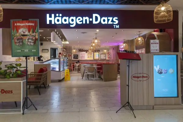 Bali, Endonezya - 17 Aralık 2024: Bali 'deki Icon Bali Alışveriş Merkezi. Haagen-Dazs mağazasının parlak pembe ve beyaz bir renk şeması var, dışarıya birkaç saksı ve sandalye yerleştirilmiş..