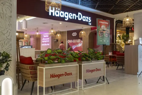 Bali, Endonezya - 17 Aralık 2024: Bali 'deki Icon Bali Alışveriş Merkezi. Haagen-Dazs mağazasının parlak pembe ve beyaz bir renk şeması var, dışarıya birkaç saksı ve sandalye yerleştirilmiş..