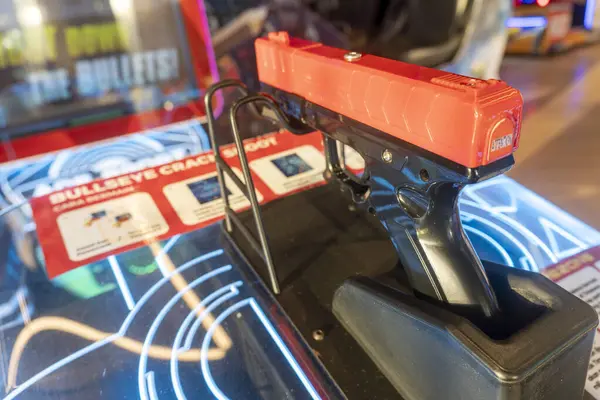 Bali, Endonezya - 17 Aralık 2024: Kırmızı silah bir oyunda sergileniyor. Tabanca bir hedef tahtası ve tezgahta duruyor.