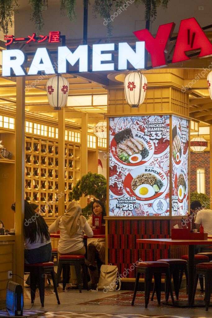 Bali, Indonesia - Dec 17, 2024: Trans Studio Mall in Bali. Ramen restaurant with people sitting at tables. The restaurant is brightly lit and has a red and white sign that says 