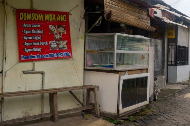 Jakarta, Endonezya - 9 Şubat 2025: küçük açık hava yiyecek standı. Kürsünün yanında bir bank var.