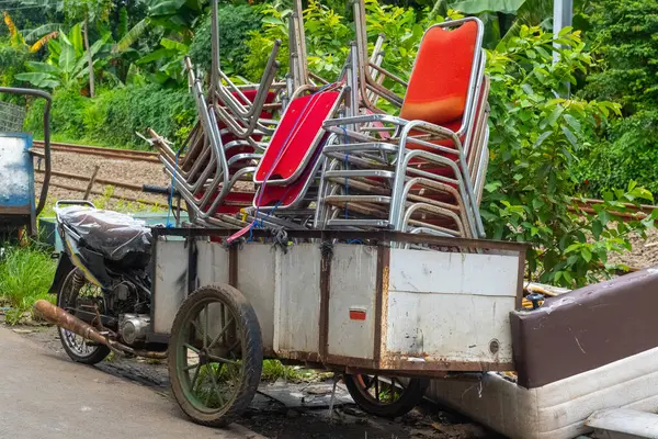 Önüne bir araba eklenmiş bir motosiklet. Sandalyeler üst üste istiflenmiş. Sahne dağınıklık ve dağınıklık hissi veriyor.